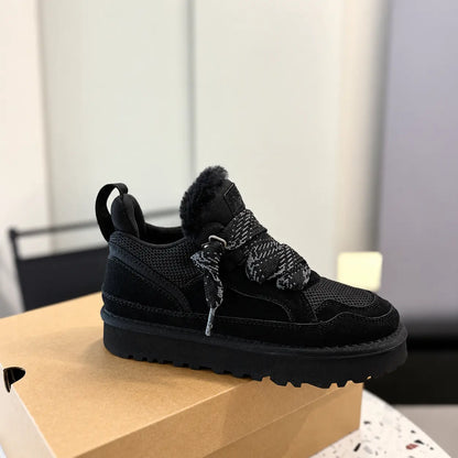 A black low-top sneaker with a fuzzy collar, black mesh and suede upper, chunky sole, and knotted black-and-white laces, resting on a brown shoebox in an indoor setting.
