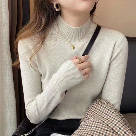 Woman wearing a ribbed light-colored turtleneck sweater, accessorized with hoop earrings, a delicate necklace, and rings—cozy, elegant, and perfect for chilly days.