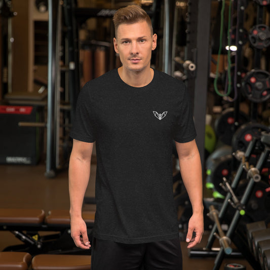 Black athletic t-shirt featuring a sharp geometric bat logo in white on the left side of the chest, worn in a gym environment with various exercise equipment—sleek, edgy, and perfect for fitness and casual wear.