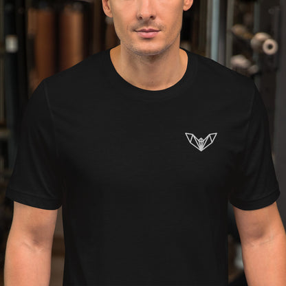 Black athletic t-shirt featuring a sharp geometric bat logo in white on the left side of the chest, worn in a gym environment with various exercise equipment—sleek, edgy, and perfect for fitness and casual wear.